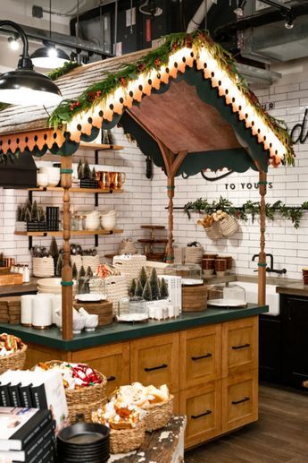 an open kitchen with lots of food on the counter and lights hanging from the ceiling