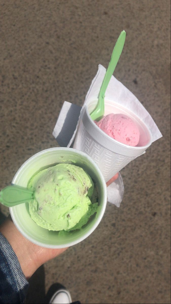 two ice creams in plastic cups with green and pink toppings on the top