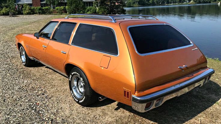 an orange station wagon parked next to a lake