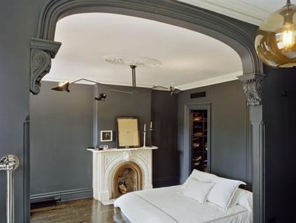 a bedroom with gray walls and white bedding in the center, along with a fireplace