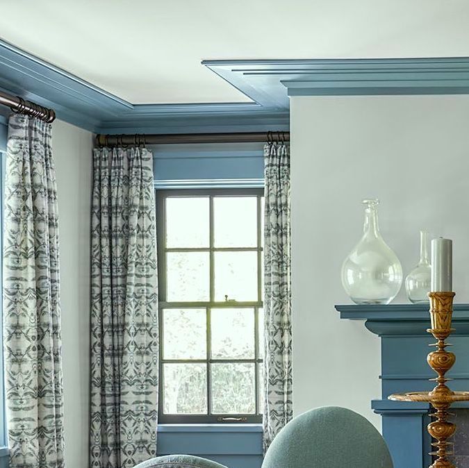 a living room filled with furniture and blue walls next to a window covered in curtains