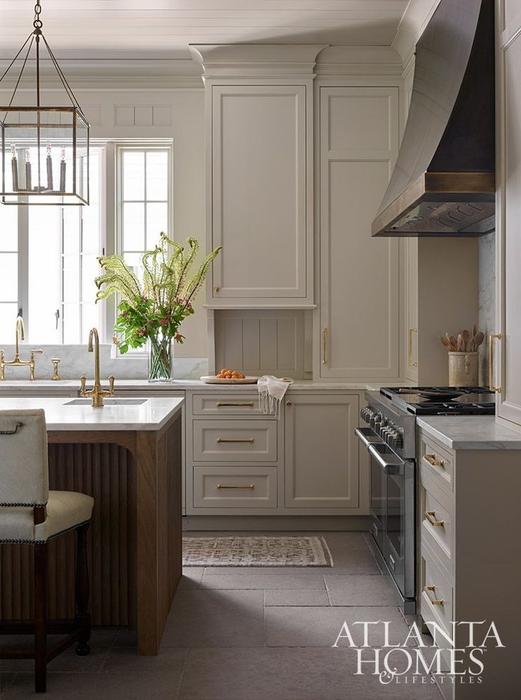 a large kitchen with white cabinets and an island in the middle is decorated with greenery