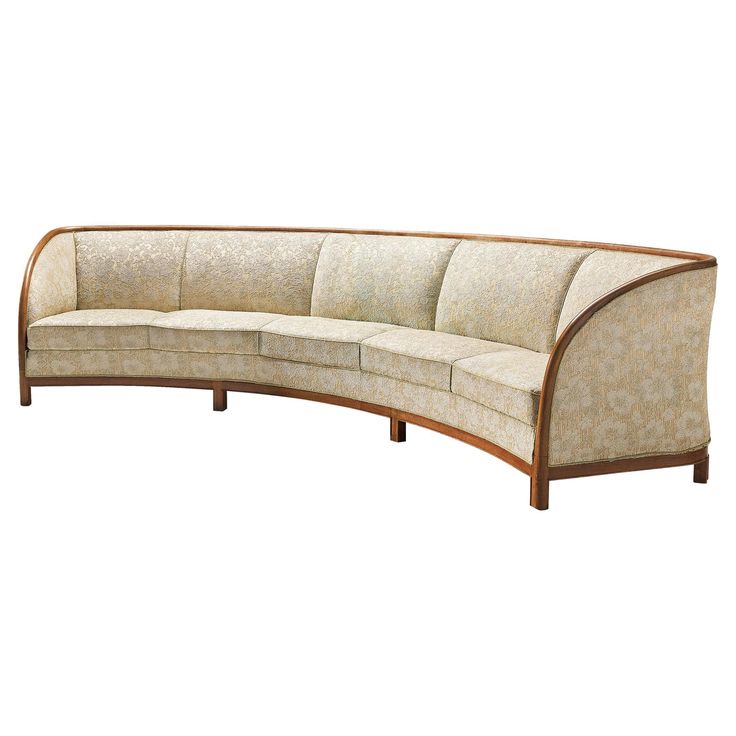 a curved sectional sofa with wooden legs and upholstered backrests on an isolated white background