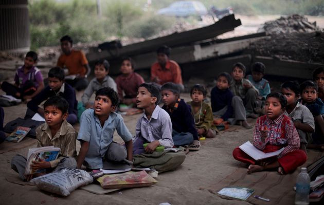 a group of children sitting on the ground in front of a sign that says mission education