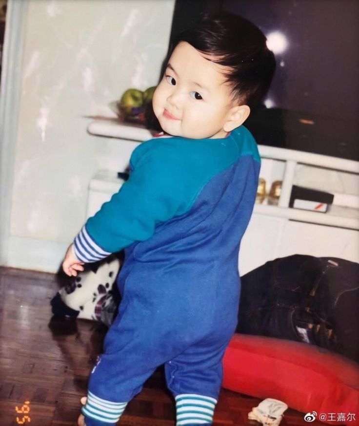 a little boy standing on top of a hard wood floor next to a tv monitor