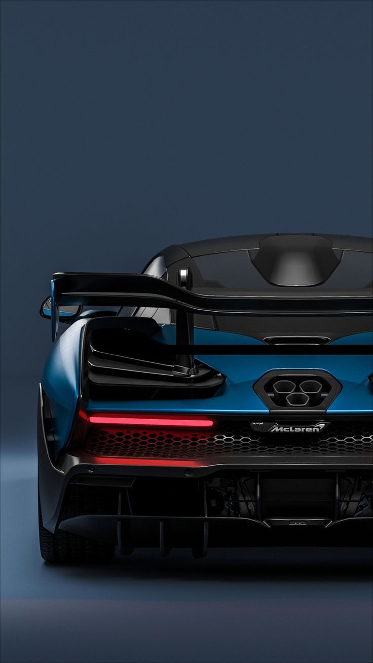 the rear end of a blue sports car on a dark background with its lights on