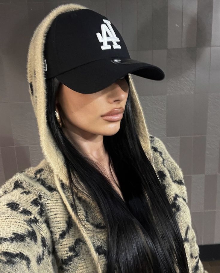 a woman with long black hair wearing a los angeles dodgers baseball cap and hoodie