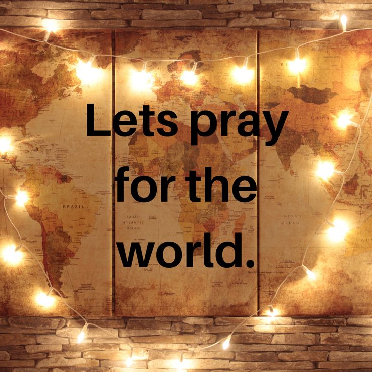 the words lets pray for the world are lit up against a brick wall with lights around it