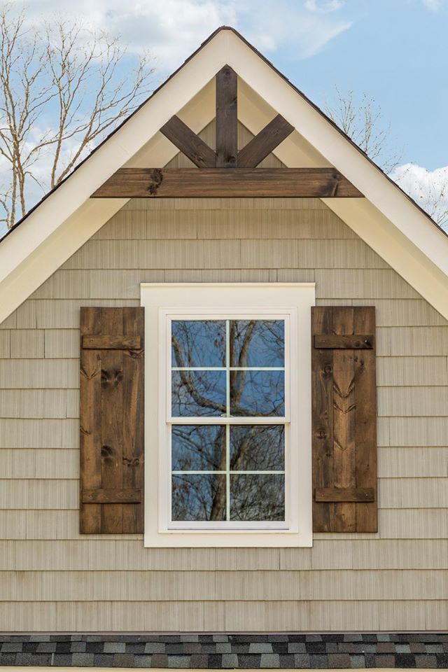 an open window on the side of a house with wood shutters and shingles