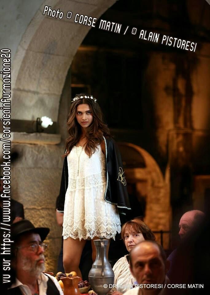 a woman is walking down the runway in a white dress and black jacket with a crown on her head