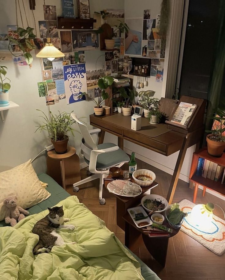 a cat laying on top of a bed next to a table with plants in it