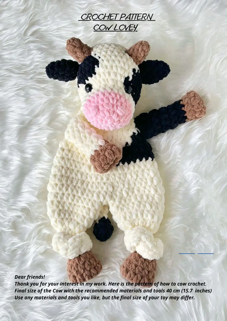 a crocheted cow laying on top of a white blanket