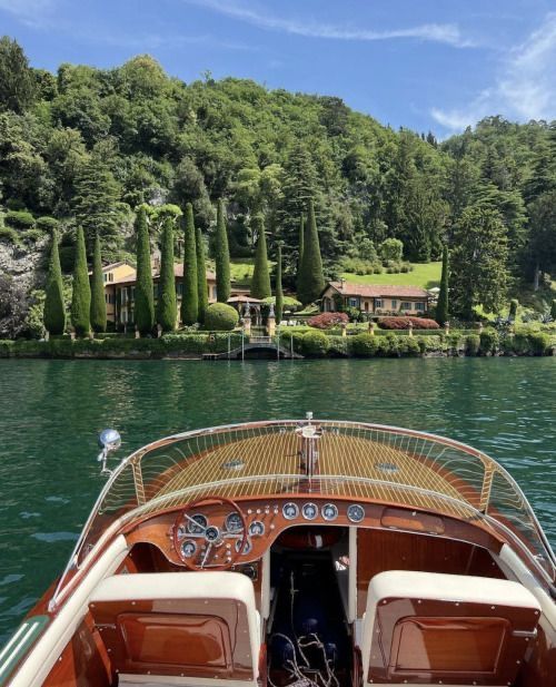 there is a boat that is in the water near some trees and houses on the shore