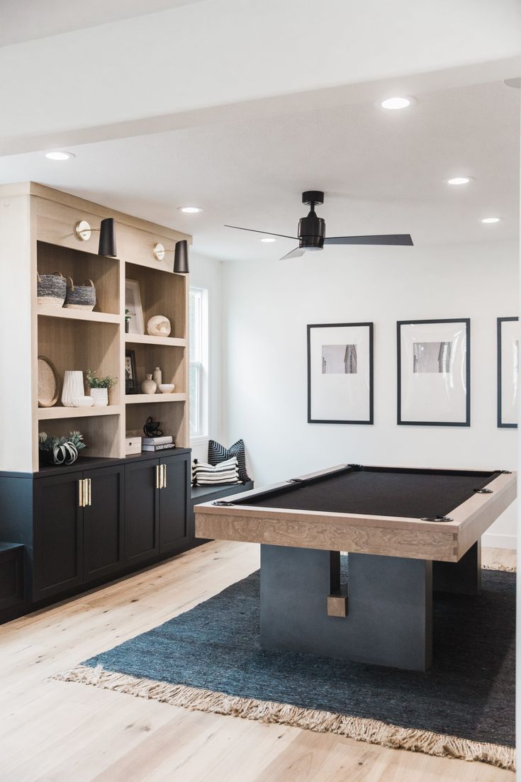 a pool table in the middle of a living room with built - in bookcases