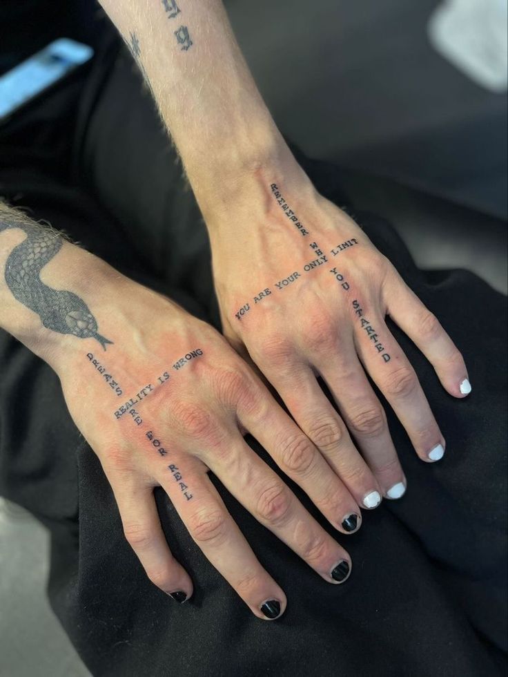 a woman's hand with tattoos on it and the words written across her fingers