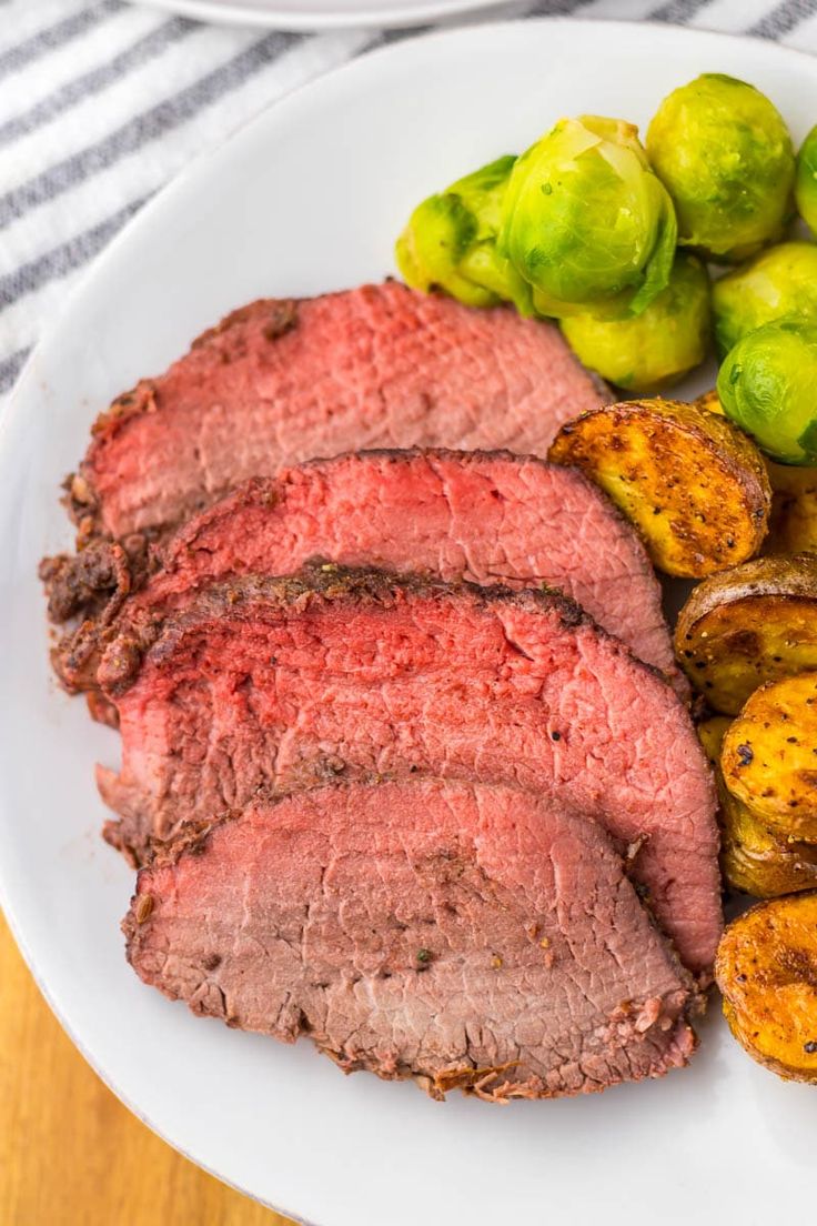 a white plate topped with meat and potatoes next to brussel sprouts