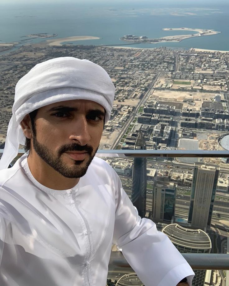 a man wearing a white turban standing on top of a building