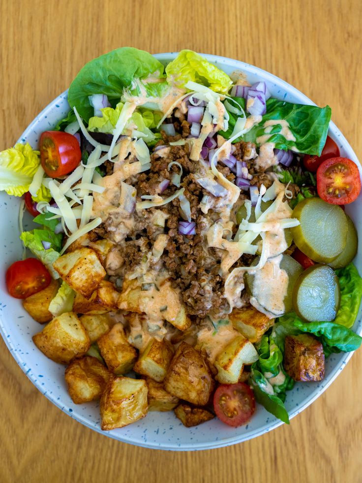 a salad with dressing and vegetables in a bowl on a wooden table, ready to be eaten