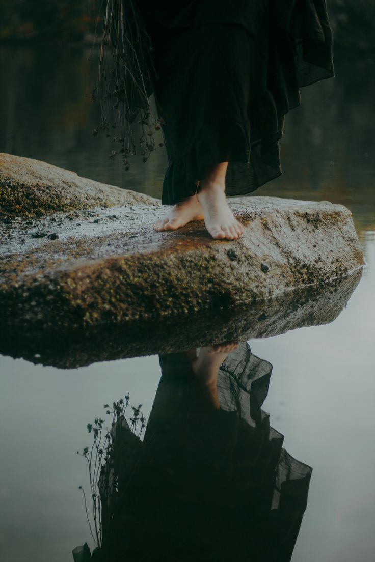 a person standing on top of a rock in the water