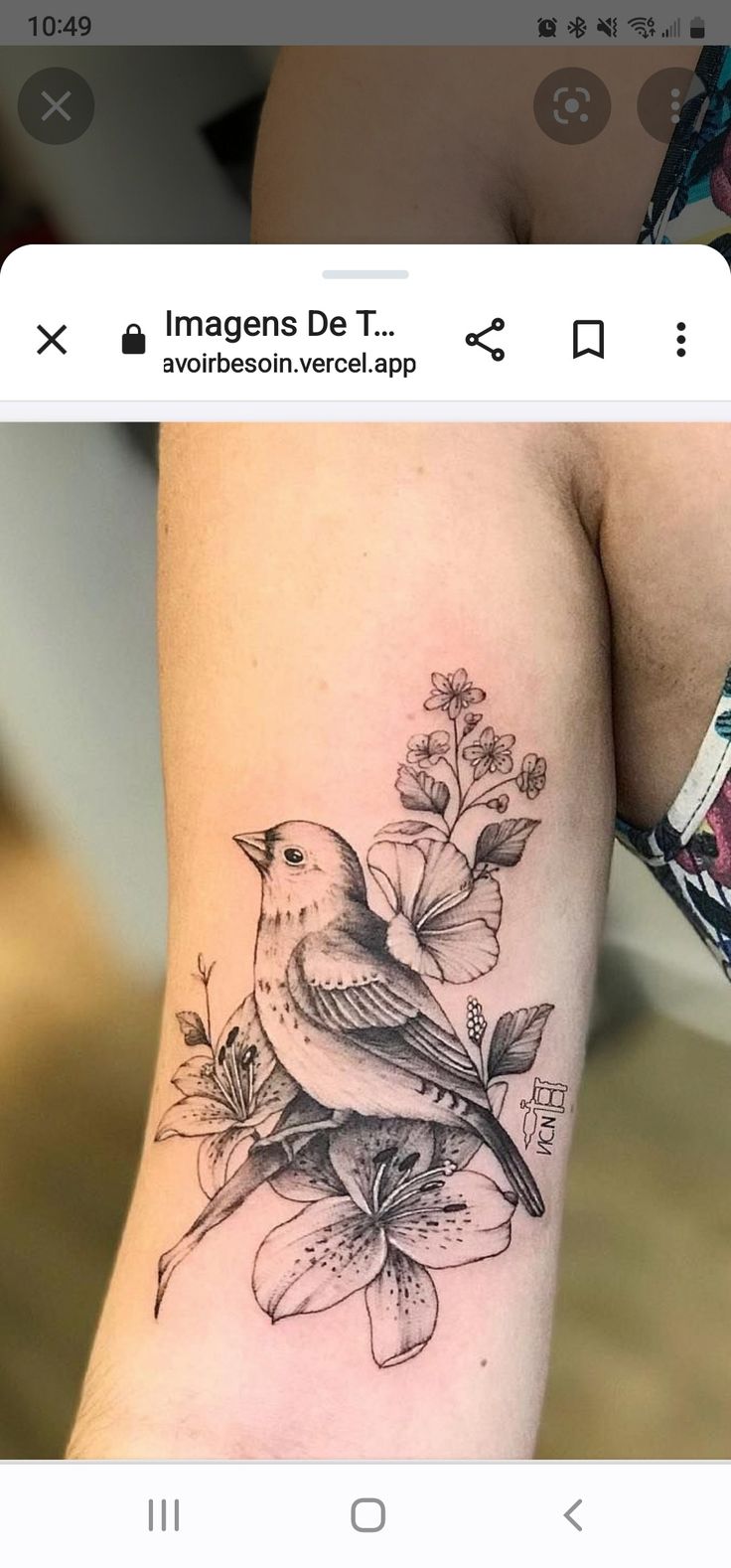 a bird sitting on top of a flower next to a person's leg with tattoos