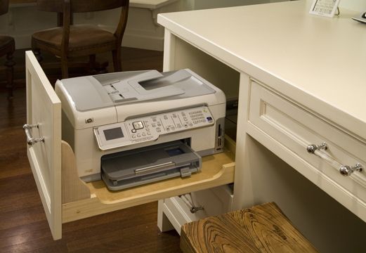 a printer sitting on top of a wooden drawer in a kitchen next to a desk