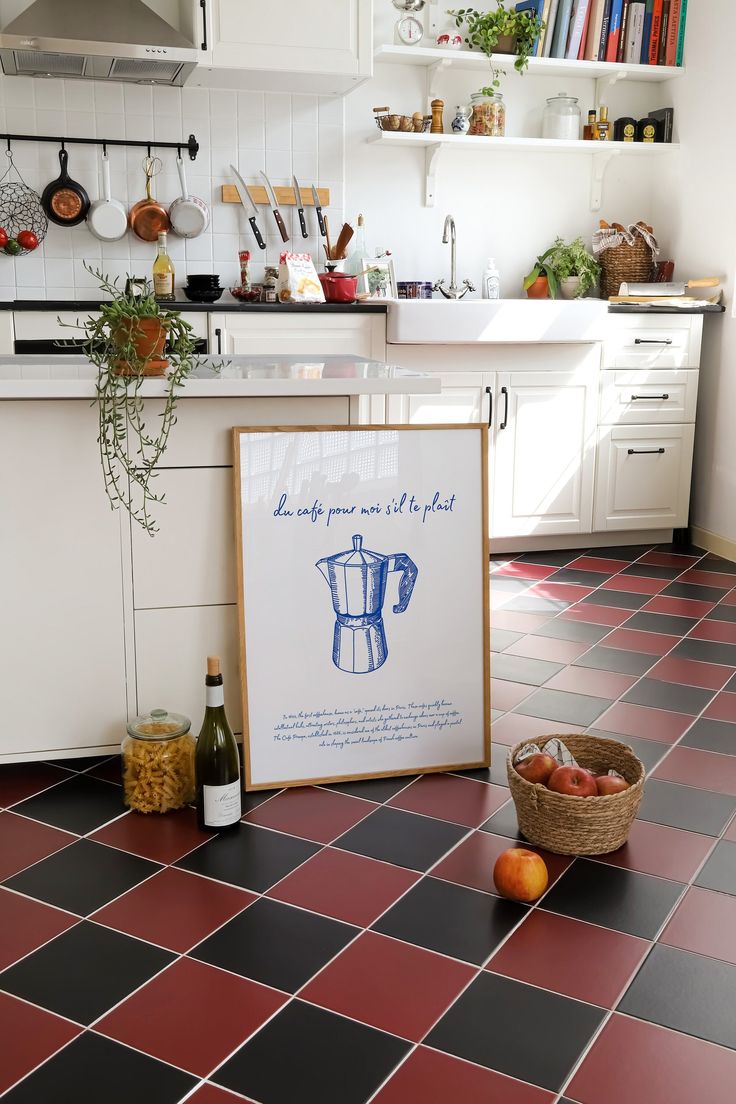 a kitchen with red and black tile flooring, white cabinets and an orange basket on the counter