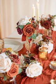 the table is set with red and white flowers, candles, and gold dishes on it