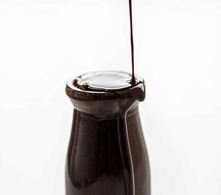 chocolate syrup being poured into a glass jar