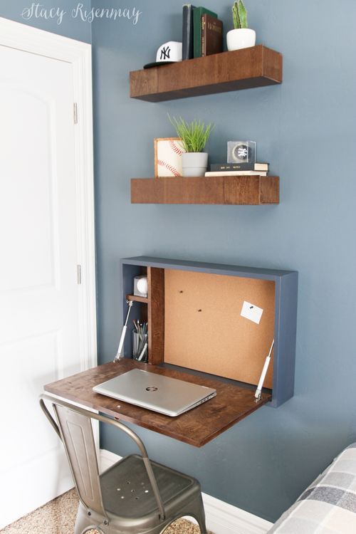 a laptop computer sitting on top of a wooden desk next to a wall mounted bookshelf