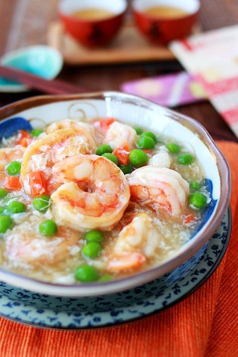 a bowl filled with shrimp and peas on top of a table