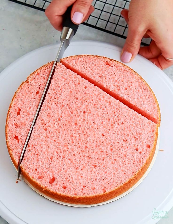 a person cutting into a cake with a knife on a white plate next to a wire rack