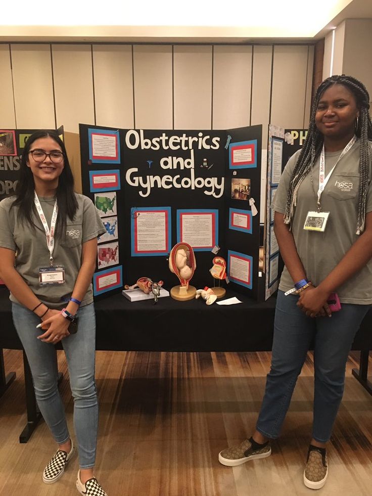 two women standing in front of a table with information about obstetrics and gyncology on it