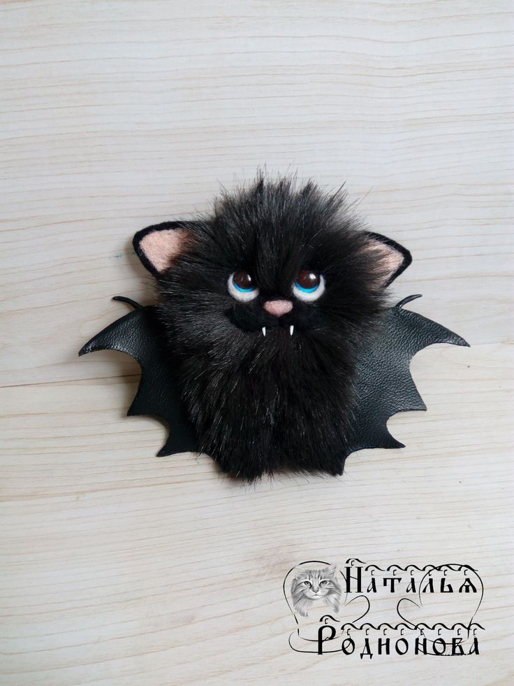 a small black bat with blue eyes on a wooden surface