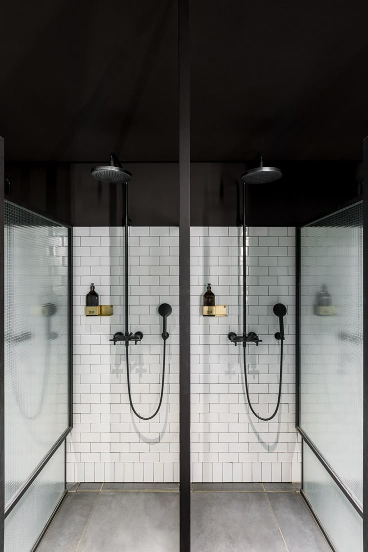 two black and white shower heads in a bathroom with tiled walls, flooring and lighting