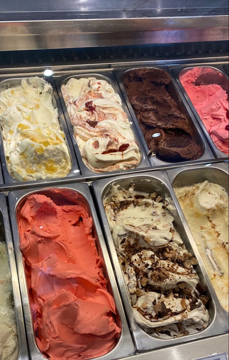 an assortment of ice creams in trays on display