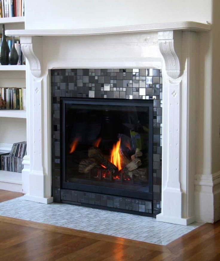 a fire place in a living room next to a book shelf with books on it