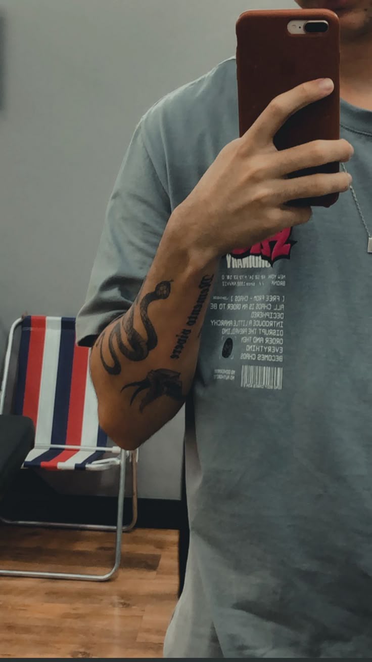 a man is taking a selfie in the mirror with his cell phone and tattoos on his arm