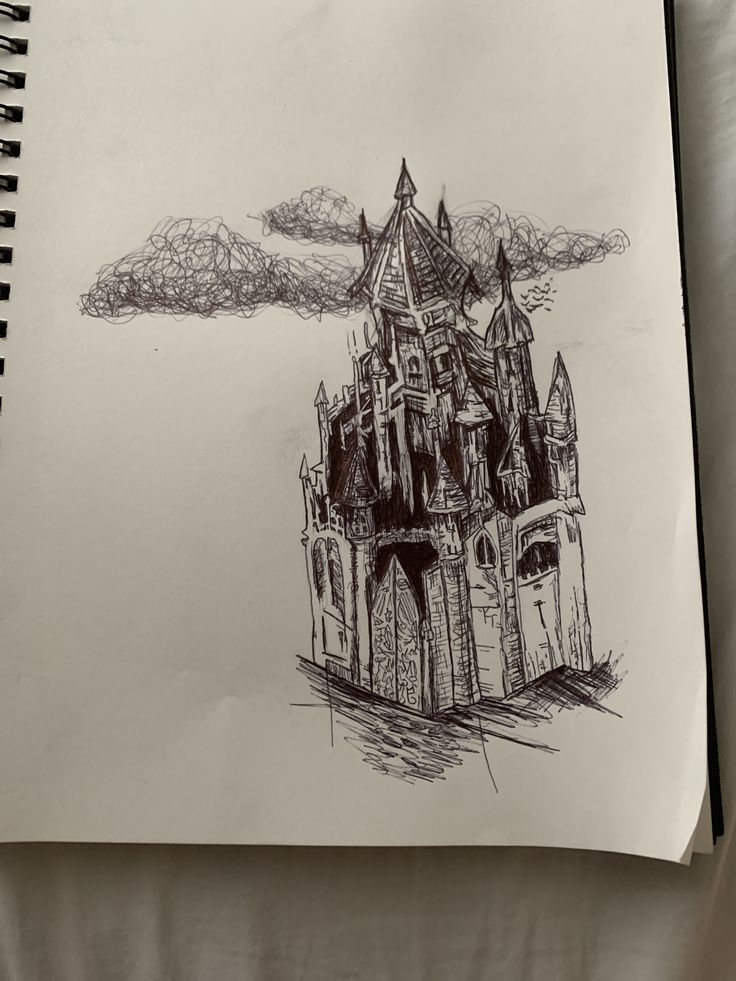 a drawing of a castle on top of a bed next to a book with writing underneath it