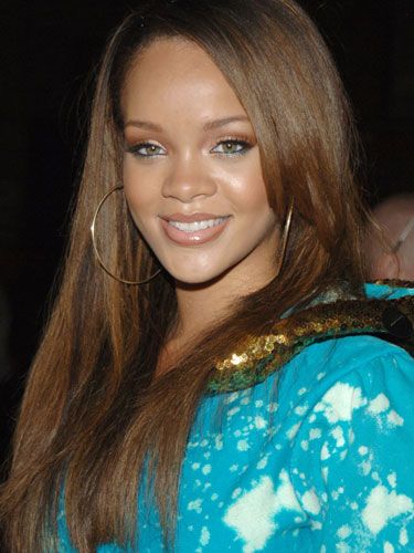 a close up of a person wearing a blue shirt and gold hoop earrings with long hair