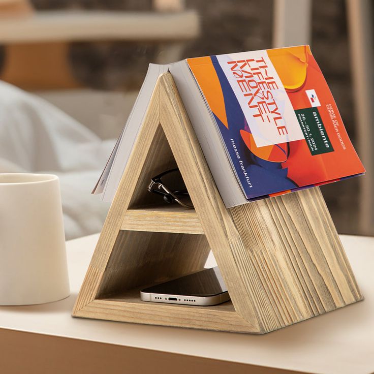 a wooden book stand with two books on it and a coffee cup next to it