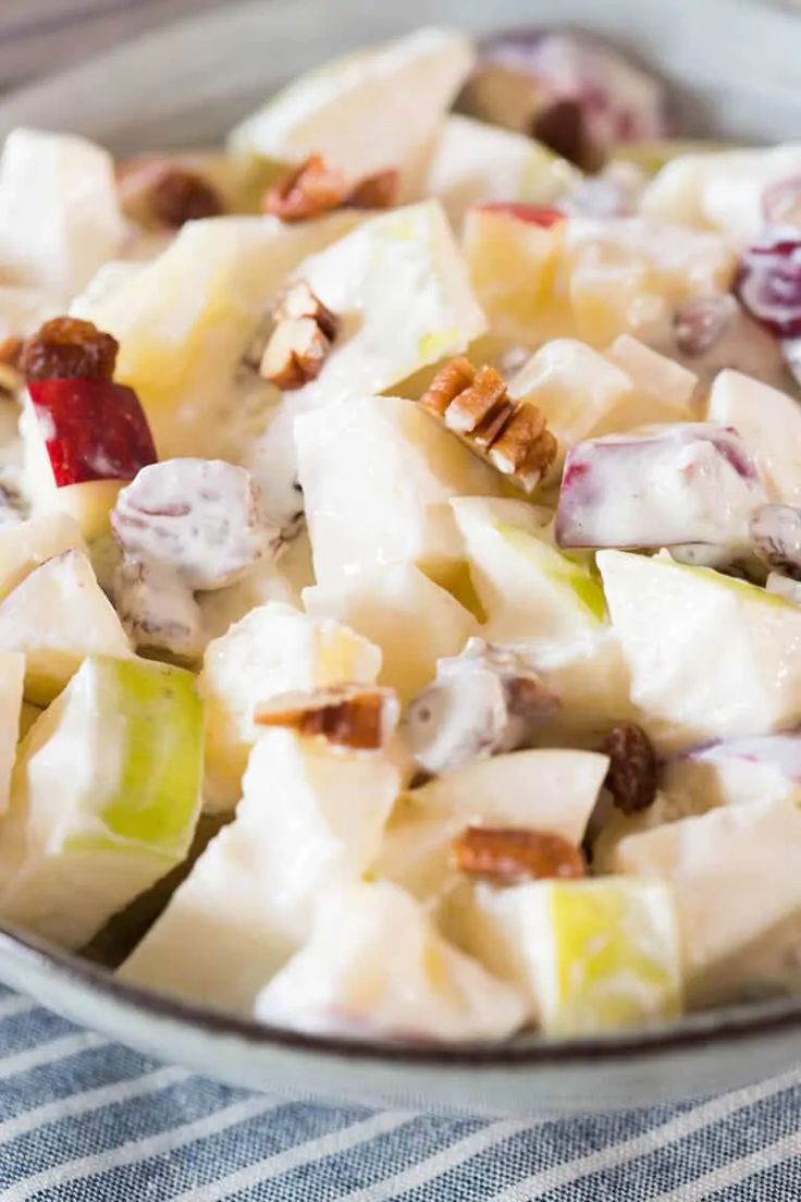 a bowl full of fruit salad with nuts and cranberries on top, ready to be eaten