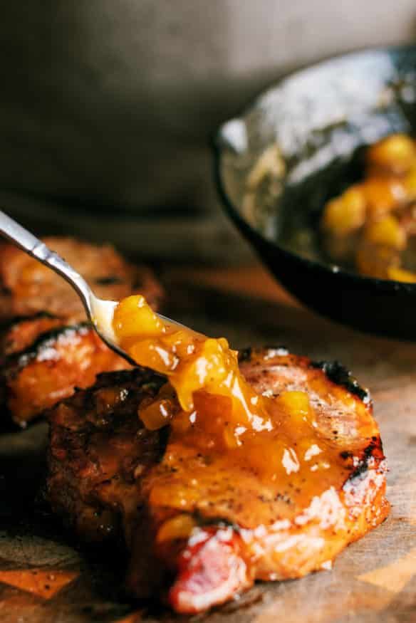 a close up of food on a wooden table with a spoon in it and another bowl behind it