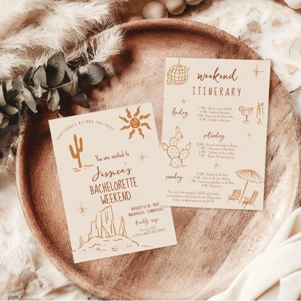 two wedding stationery cards sitting on top of a wooden plate