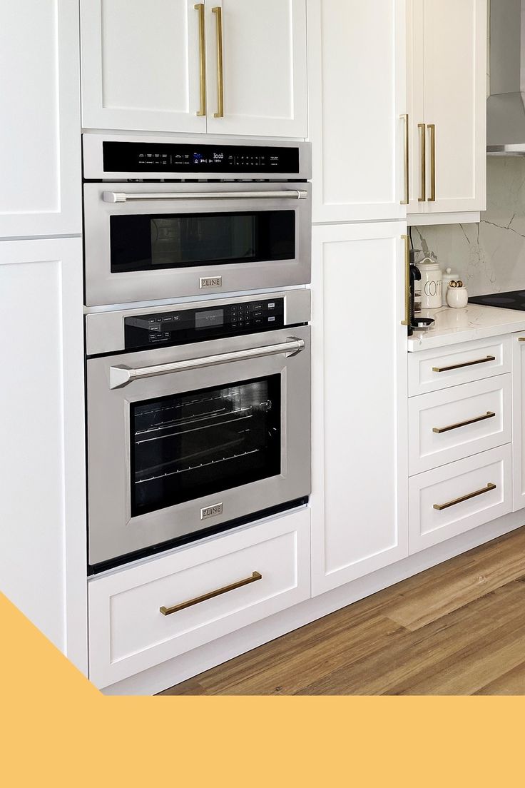 two ovens in a kitchen with white cabinets and wood flooring on the walls