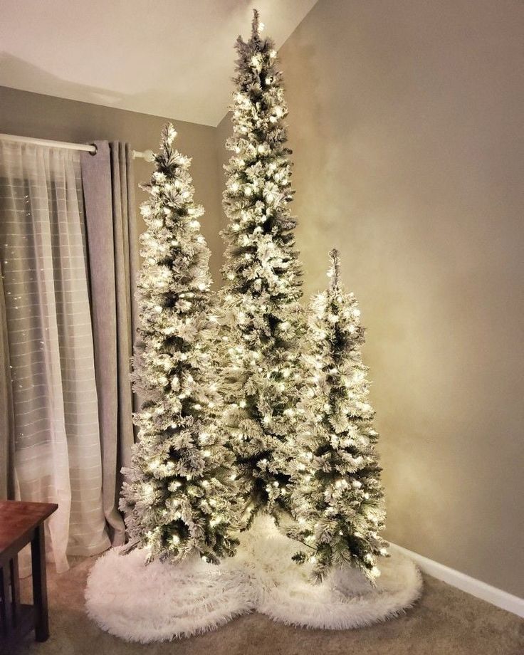 two white christmas trees in a living room