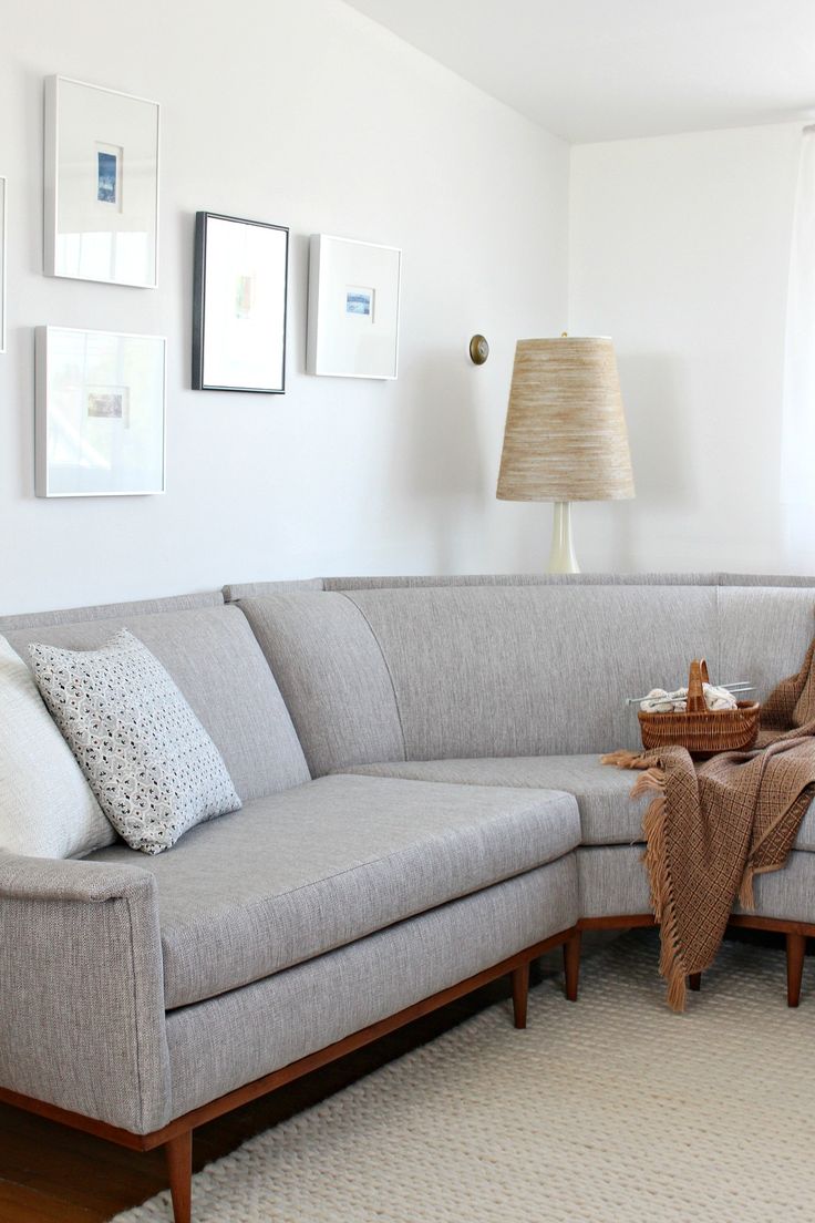 a living room with a large sectional couch and coffee table in the corner, along with pictures on the wall