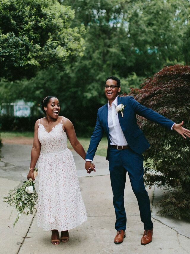 a man and woman holding hands walking down a sidewalk