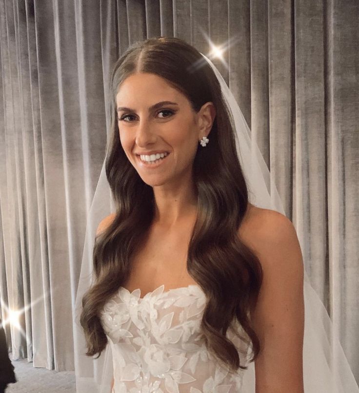 a woman in a wedding dress and veil posing for the camera with her hair down