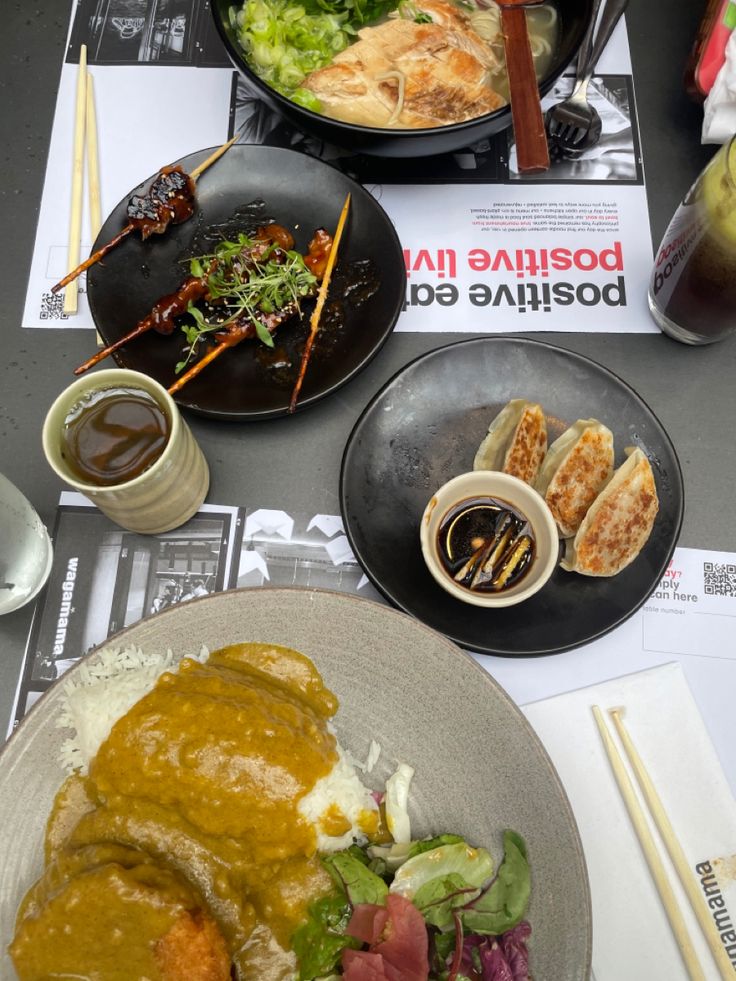 a table topped with plates of food and chopsticks