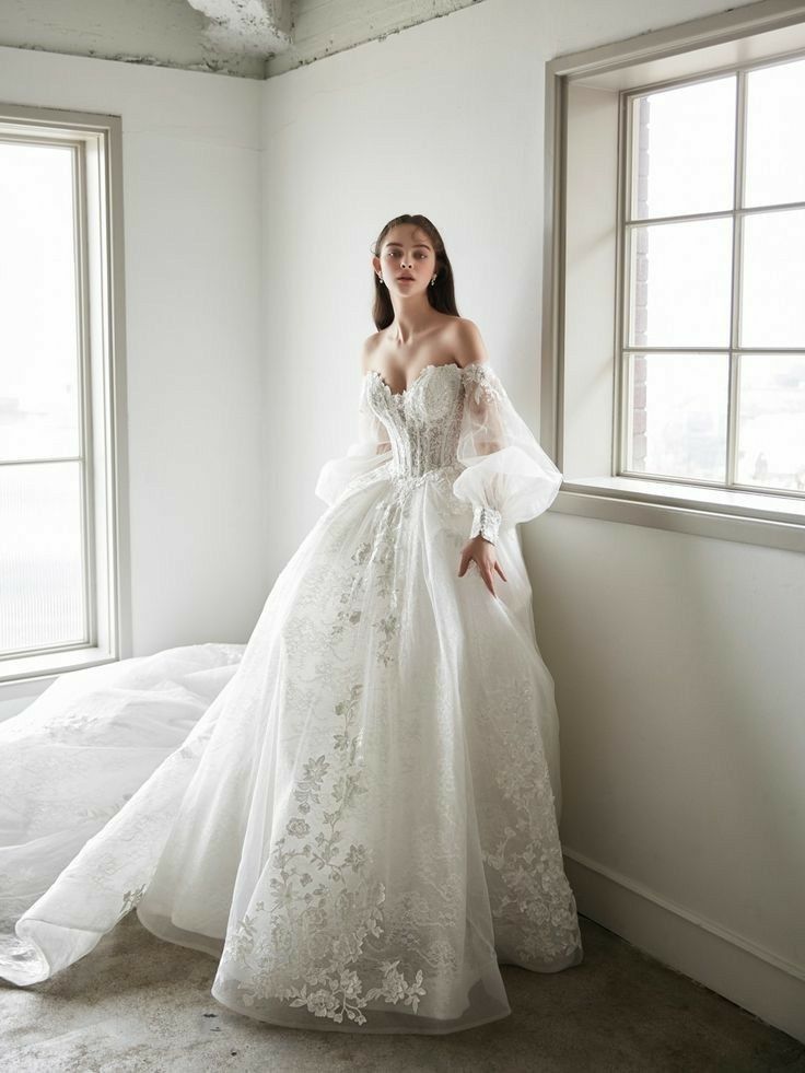 a woman in a white wedding dress leaning against a window